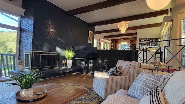living room featuring a towering ceiling, wood finished floors, brick wall, beam ceiling, and a large fireplace