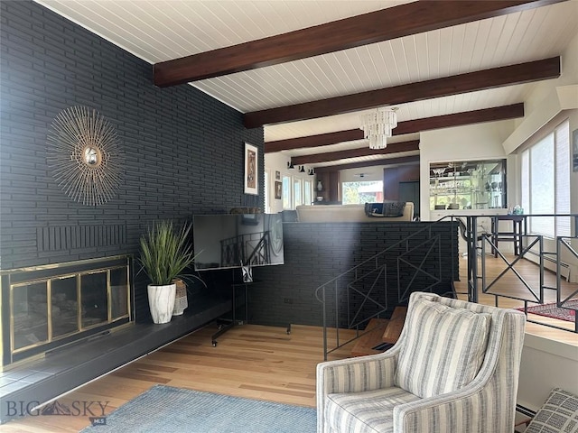 living area with beam ceiling, brick wall, and wood finished floors