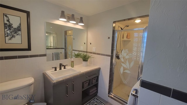 full bathroom with vanity, a shower stall, toilet, and tile walls