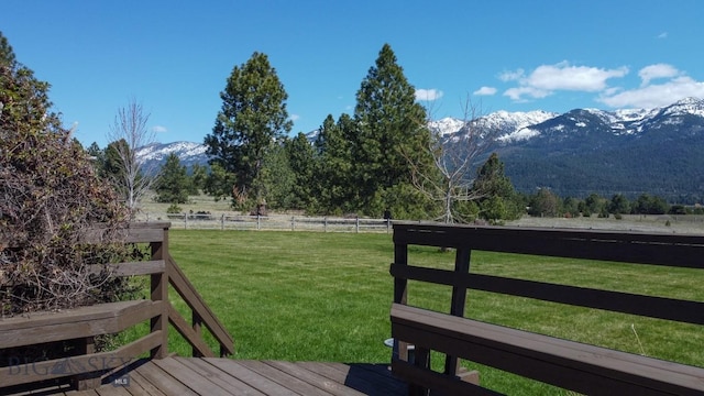 deck with a mountain view, a yard, a rural view, and fence