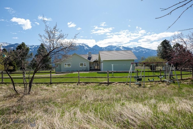 view of side of home with a yard, fence, a mountain view, and a playground