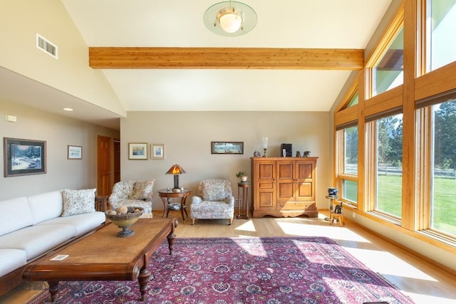 living area with a healthy amount of sunlight, beamed ceiling, light wood-type flooring, and visible vents