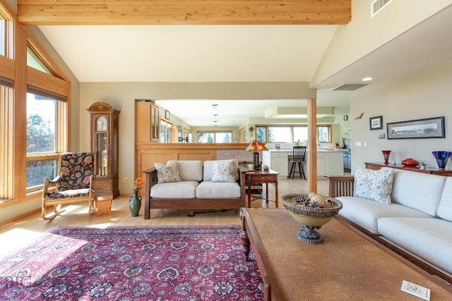 living room featuring lofted ceiling with beams, light wood finished floors, and visible vents