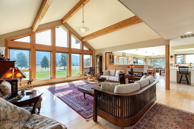 living area with visible vents, light wood-style floors, high vaulted ceiling, and beamed ceiling