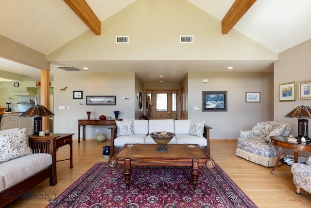 living room featuring visible vents, light wood-style flooring, and beamed ceiling