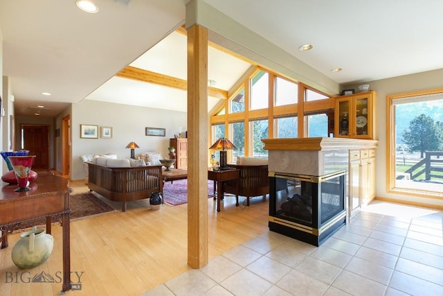 living room featuring light tile patterned floors, a multi sided fireplace, vaulted ceiling, and a wealth of natural light