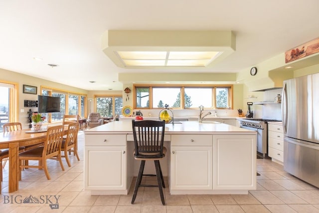 kitchen with light countertops, appliances with stainless steel finishes, white cabinets, and a wealth of natural light