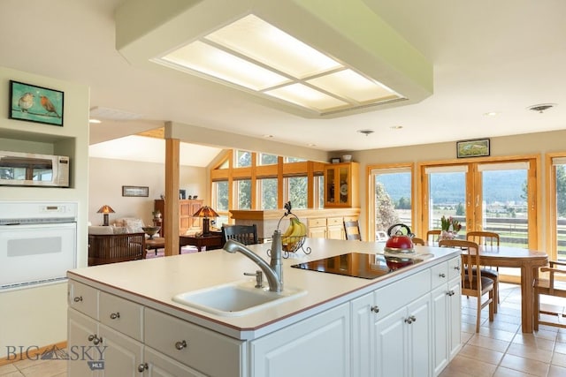 kitchen featuring a sink, black electric stovetop, light tile patterned flooring, and white oven