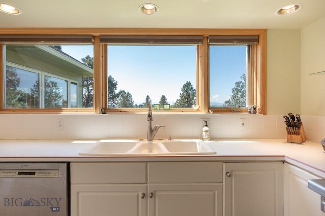 kitchen featuring a sink, white cabinets, backsplash, and dishwasher