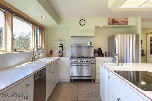 kitchen with white cabinets, light tile patterned flooring, appliances with stainless steel finishes, and a sink