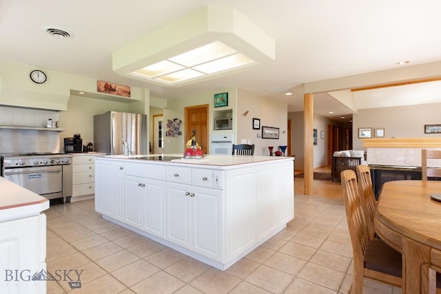 kitchen with light tile patterned floors, appliances with stainless steel finishes, white cabinets, and light countertops