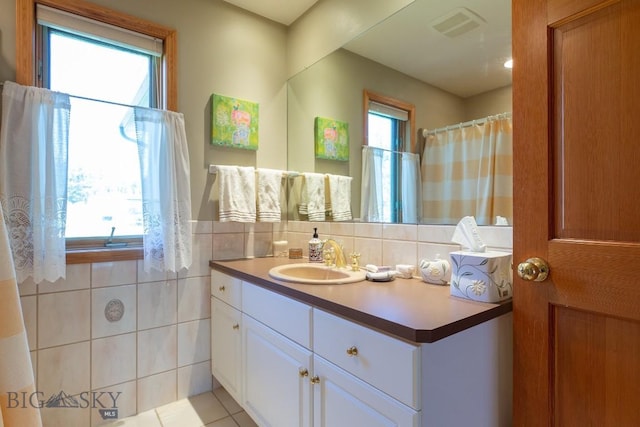 full bath with tile patterned flooring, tile walls, visible vents, and vanity