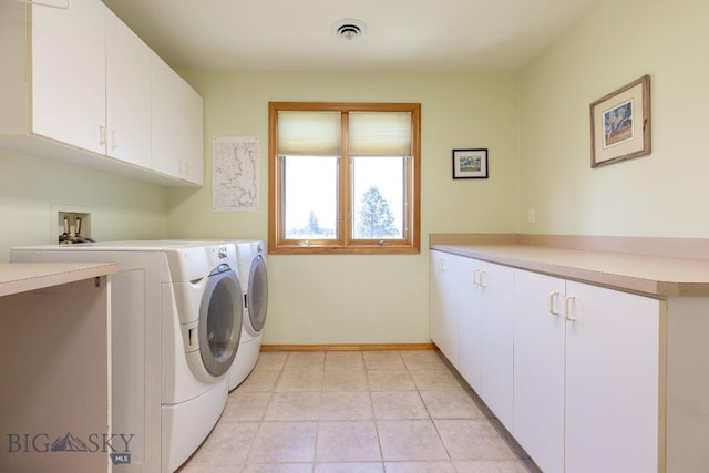 laundry area with baseboards, washing machine and dryer, cabinet space, and visible vents