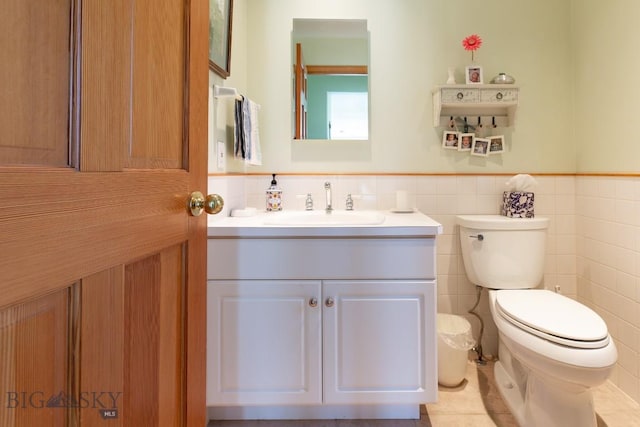 half bath with a wainscoted wall, toilet, and tile walls