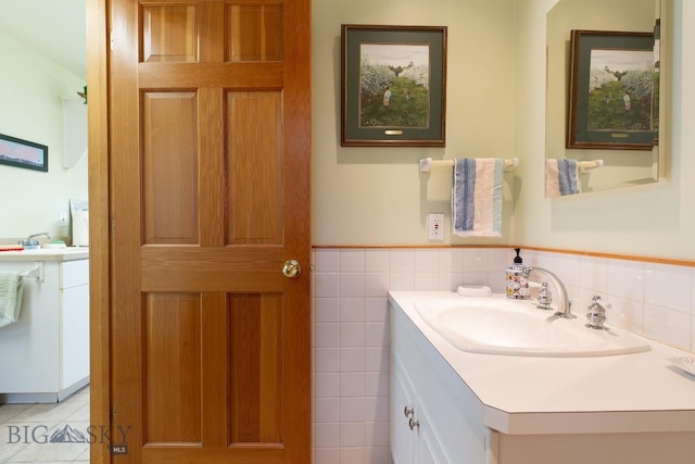 bathroom with vanity, a wainscoted wall, and tile walls