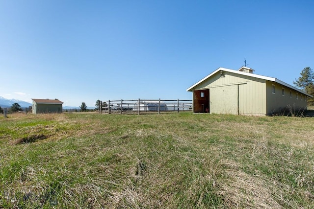 view of yard with an outdoor structure, a pole building, and fence