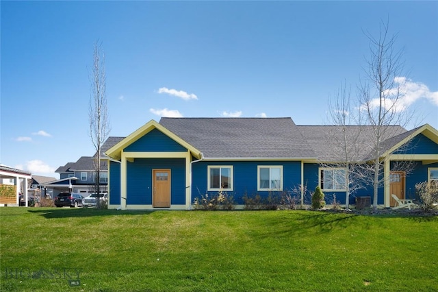 view of front of home with a shingled roof and a front lawn