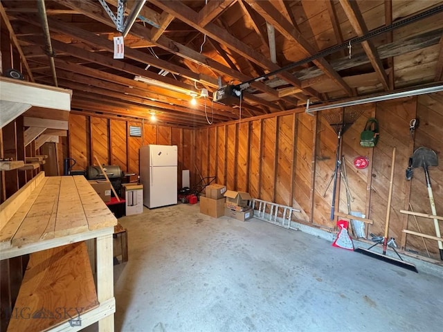 216 W 2nd Ave, Big Timber, MT 59011 - garage with freestanding refrigerator, wooden walls, and a garage door opener