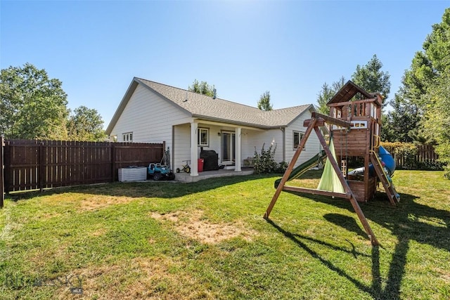 rear view of house featuring a yard, a fenced backyard, a playground, and a patio area