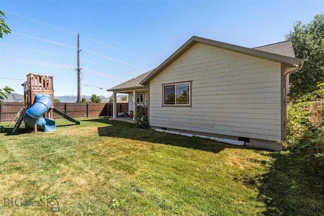 rear view of house featuring a lawn, a playground, fence, and crawl space