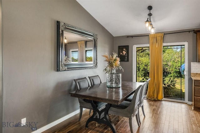 dining area featuring baseboards, vaulted ceiling, and wood finished floors