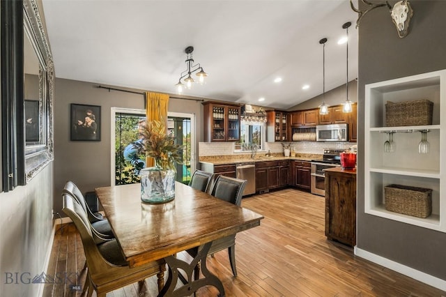 kitchen featuring vaulted ceiling, decorative backsplash, stainless steel appliances, and a wealth of natural light
