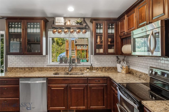 kitchen featuring a sink, light stone counters, tasteful backsplash, and stainless steel appliances