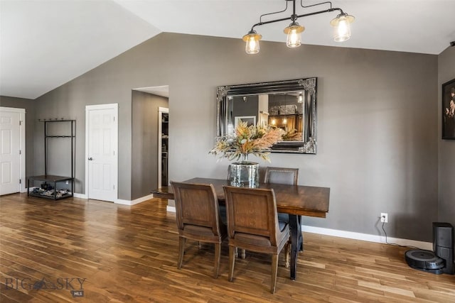 dining space featuring baseboards, vaulted ceiling, and wood finished floors