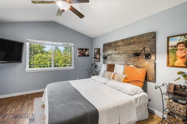 bedroom featuring a ceiling fan, visible vents, wood finished floors, baseboards, and lofted ceiling