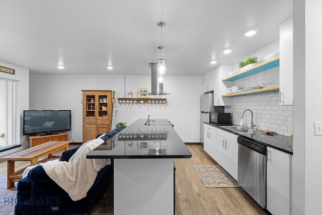 kitchen with stainless steel dishwasher, open shelves, dark countertops, and a sink