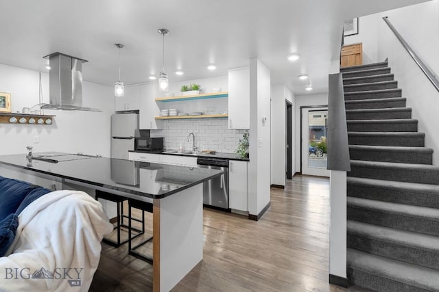 kitchen with stainless steel dishwasher, open shelves, dark countertops, white cabinetry, and island exhaust hood