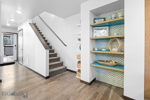 stairway featuring baseboards, wood finished floors, and visible vents