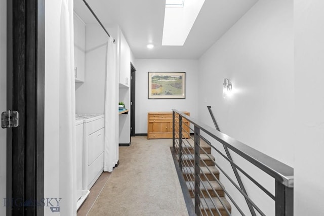 corridor with carpet floors, a skylight, an upstairs landing, and washing machine and dryer