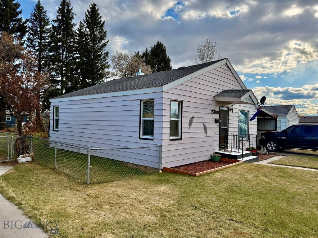 view of front of property with roof with shingles, fence, and a front yard
