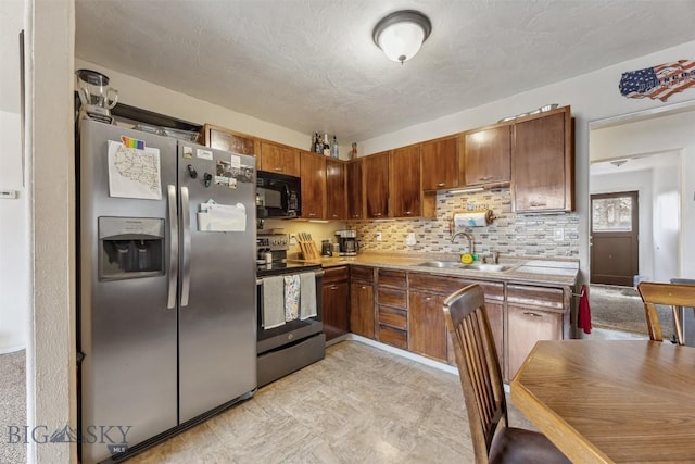 2300 S Dr, Butte, MT 59701 - kitchen with a sink, brown cabinetry, stainless steel appliances, light countertops, and decorative backsplash