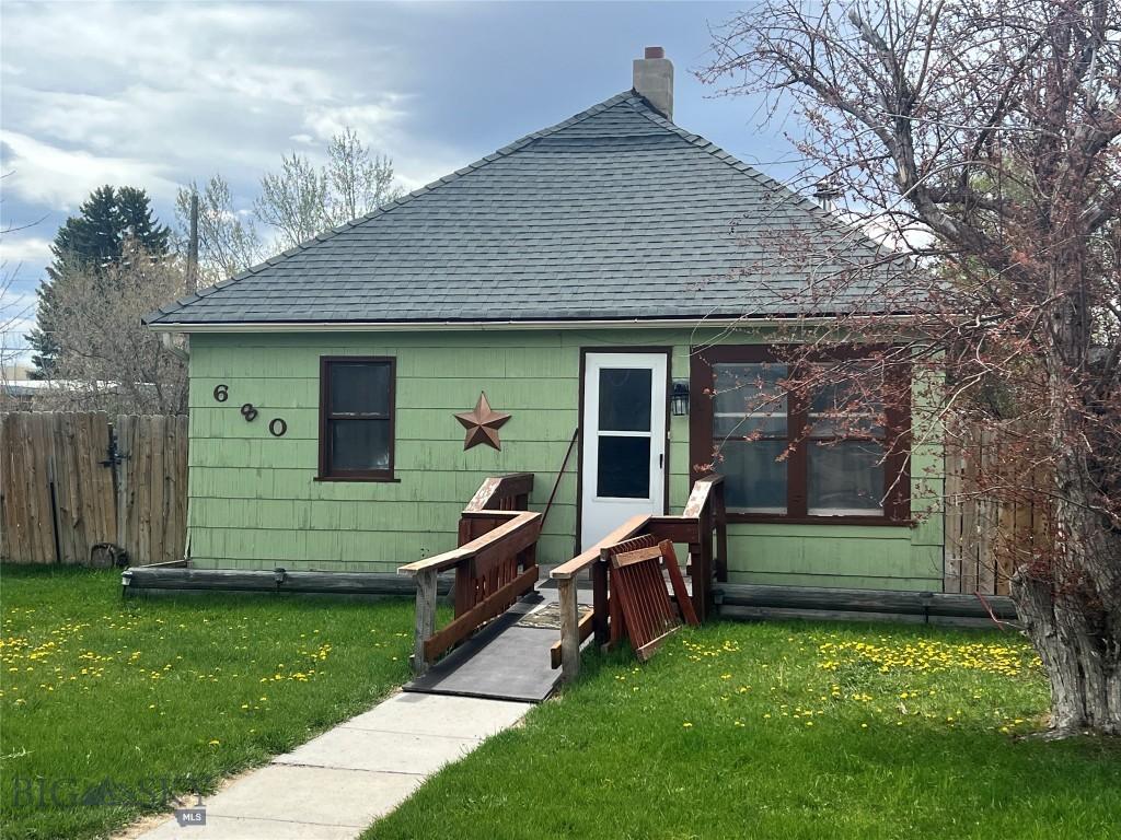 back of property featuring a lawn, a shingled roof, fence, and a chimney