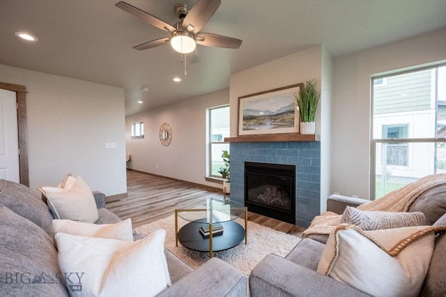 living area featuring recessed lighting, a ceiling fan, wood finished floors, and a tile fireplace