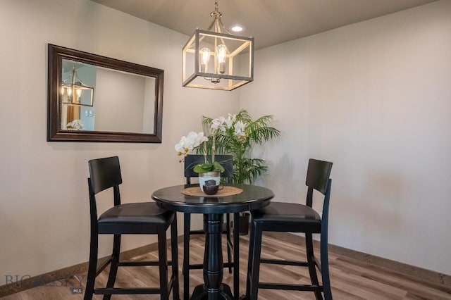 dining space with baseboards, wood finished floors, and a chandelier