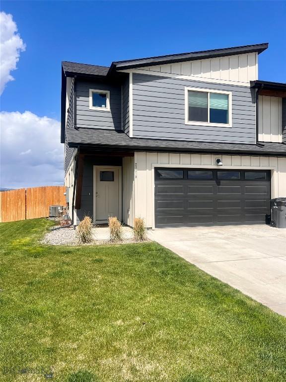 traditional-style house with an attached garage, board and batten siding, fence, and a front yard