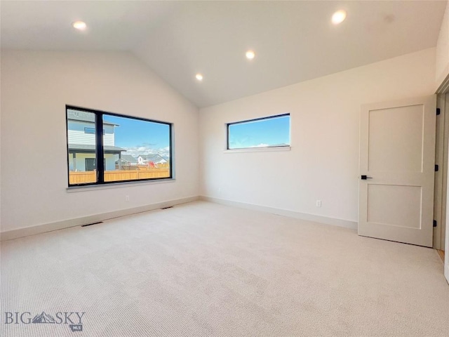 spare room featuring light carpet, recessed lighting, and lofted ceiling