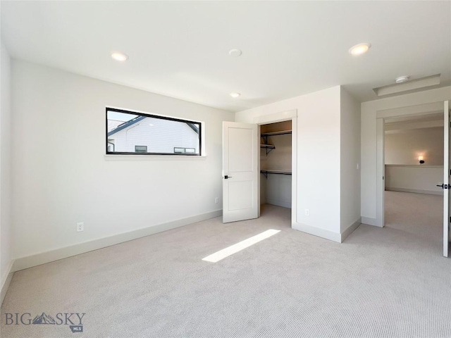 unfurnished bedroom with light colored carpet, baseboards, a closet, a spacious closet, and recessed lighting