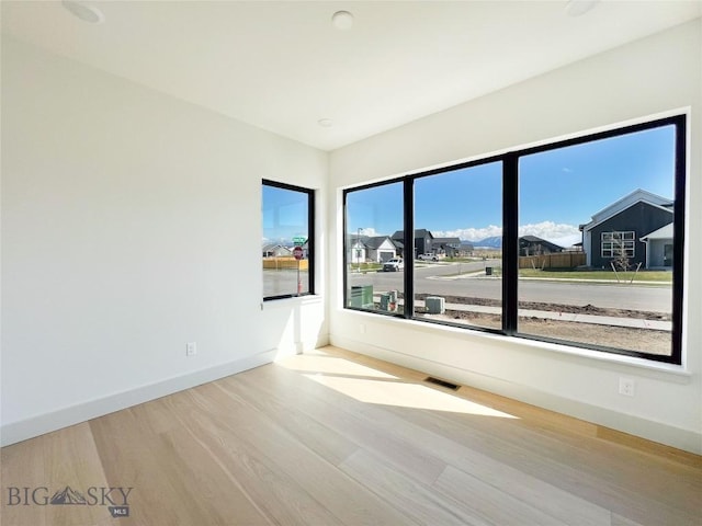 spare room with baseboards, visible vents, and wood finished floors