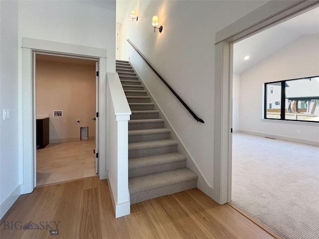 staircase featuring baseboards, vaulted ceiling, recessed lighting, and wood finished floors
