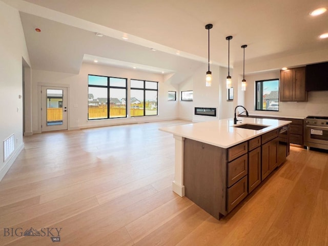 kitchen with recessed lighting, stainless steel gas range oven, a sink, and light wood-type flooring
