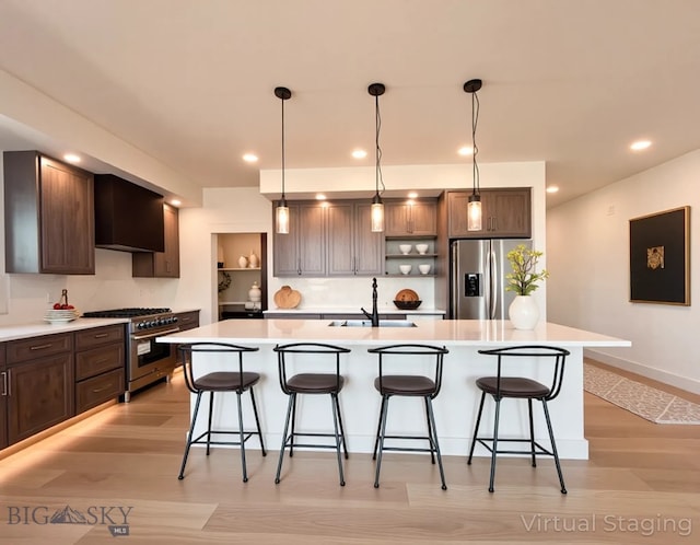 kitchen with a sink, light wood finished floors, appliances with stainless steel finishes, and a breakfast bar