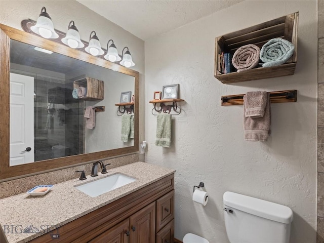full bathroom featuring vanity, a textured wall, toilet, and a shower stall