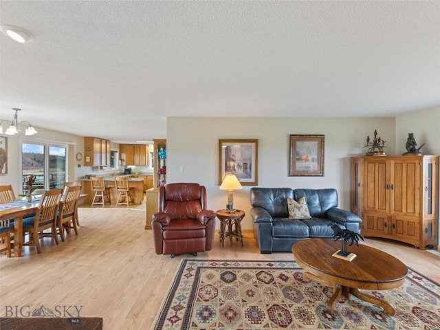 living area with a textured ceiling, a notable chandelier, and light wood-type flooring