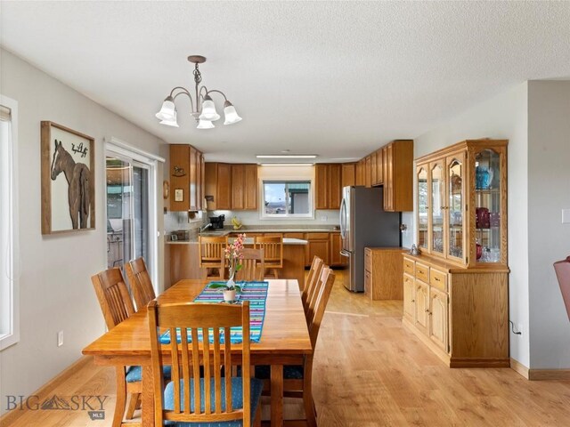 dining space with baseboards, light wood finished floors, and a notable chandelier