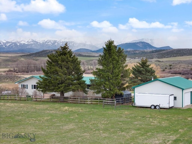 view of yard featuring an outdoor structure, fence, a mountain view, and a garage
