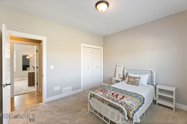 carpeted bedroom with visible vents, baseboards, and a closet